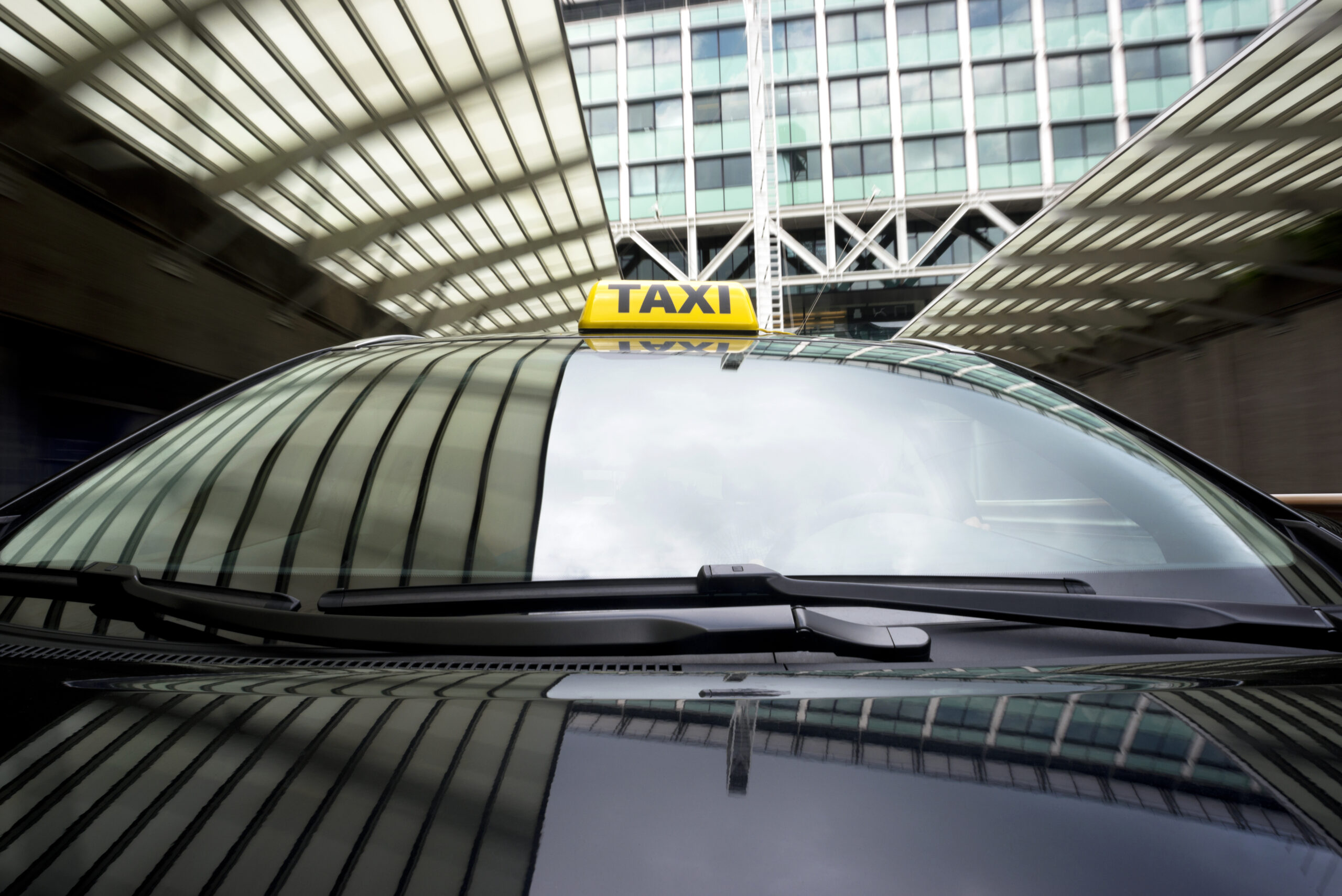 Taxi cab emerging from a garage underneath an office building.